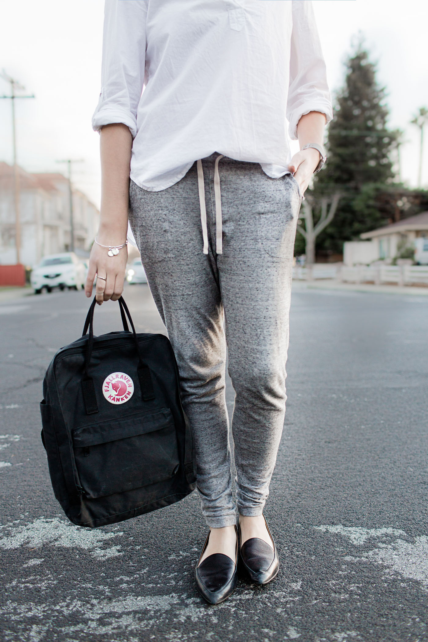 An athleisure outfit featuring relaxed joggers, a backpack, and everlane modern point flats.
