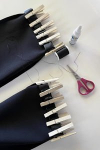 Supplies to hem vegan leather pants. Includes vegan leather pants, clothes pins, needle, thread, scissors, and no-sew glue.